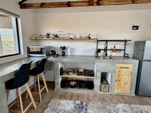 a kitchen with a counter with chairs and a stove at Manos Farm Stay in Koo