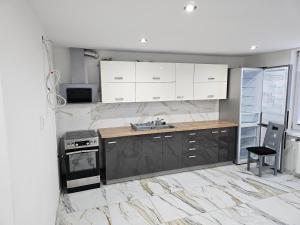 a kitchen with white cabinets and a sink and a stove at Izba v apartmáne in Šaca