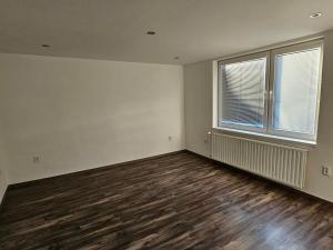 an empty living room with wooden floors and a window at Izba v apartmáne in Šaca
