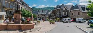 a town with a fountain in the middle of a street at La Marquise in Saint-Côme-dʼOlt