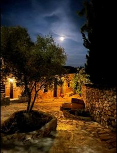 a tree in front of a stone building with a moon at La Casa Di Nonna in Koríthion