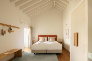 a white bedroom with a bed and a table at Moinho da Areia in Ribeira Grande