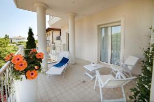 - un balcon avec des chaises blanches, une table et des fleurs dans l'établissement Hotel Gala, à Riccione