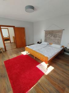 a bedroom with a large bed with a red rug at Haus am Wald Zorge 16+ Gäste in Walkenried