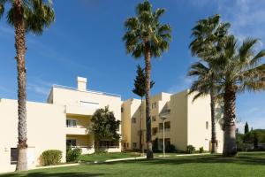 a group of palm trees in front of a building at Parque Mourabel, Oásis Village & Pé do Lago in Vilamoura