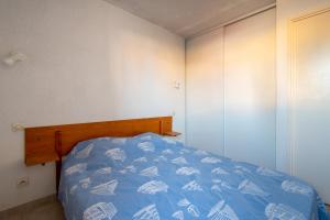 a bedroom with a bed with a blue comforter at Le Brise Marine - Terrasse - Plage - Piscine - Parking in Cap d'Agde