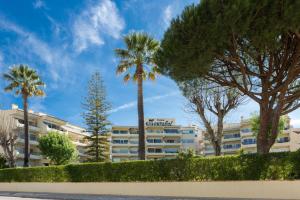 a large building with palm trees in front of it at Parque Mourabel, Oásis Village & Pé do Lago in Vilamoura +37 photos