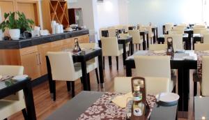 a restaurant with tables and white chairs and bottles of beer at Parque Mourabel, Oásis Village & Pé do Lago in Vilamoura