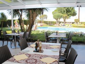a restaurant with tables and chairs and a swimming pool at Parque Mourabel, Oásis Village & Pé do Lago in Vilamoura