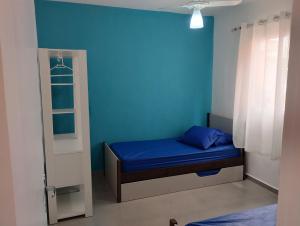a small room with a blue wall and a bed at Cantinho do descanso in Bertioga