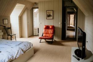 a bedroom with a bed and a red chair at Landgoed Borgerhof in Heythuysen