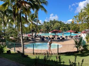 a person standing by a fence near a swimming pool at AYOUNAKA, Appartement cosy avec plage terrasse & piscine in Courcelles Sucrerie