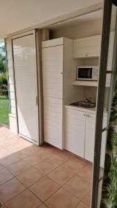 a kitchen with white cabinets and a microwave at AYOUNAKA, Appartement cosy avec plage terrasse & piscine in Courcelles Sucrerie