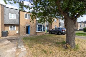un coche aparcado frente a una casa con un árbol en Large 6BR Home Central Leamington Spa Driveway WiFi, en Leamington Spa