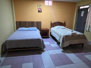 a bedroom with two beds and a tiled floor at Hospedaje El Centro in Ayacucho