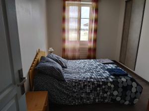 een slaapkamer met een bed met een dekbed en een raam bij Maison Noyarey in Noyarey +5 foto's