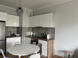 a kitchen with a white table and a table and chairs at Apartament Leśna in Bydgoszcz