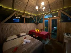 NaranjoにあるCasa del Arbol Feel Goodのベッドと小さなテーブルと赤いテーブルのある部屋