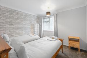 zwei Betten in einem Zimmer mit einer Ziegelwand in der Unterkunft A Charming 3 Bed home next to NEC and Birmingham International Airport in Marston Green