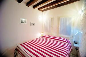 ein Schlafzimmer mit einem gestreiften Bett und einem Fenster in der Unterkunft Ca' di Paolo in Venedig
