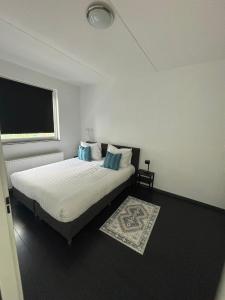 1 dormitorio con 1 cama con sábanas blancas y almohadas azules en In Almere, Close to Amsterdam, en Almere