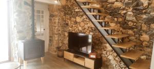 a living room with a tv and a stone wall at Casita con jardin en Sada in San Andrés de Carnoedo
