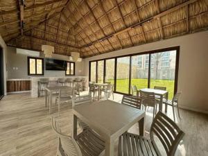 a dining room with tables and chairs and windows at Departamento acogedor con vista al mar y alberca in Conchal