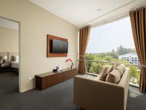 a living room with a couch and a large window at Horison TC UPI Serang in Banjar