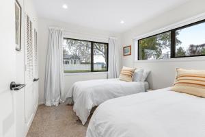 2 letti in una camera con 2 finestre di Golden Grove - Cambridge Holiday Home a Cambridge
