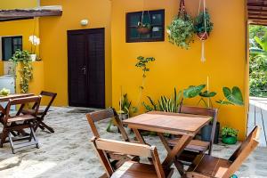 イリャベラにあるChalés da Libélula | Refúgio entre praia e natureza em Ilhabelaの黄色い壁の前にテーブルと椅子付きのパティオ