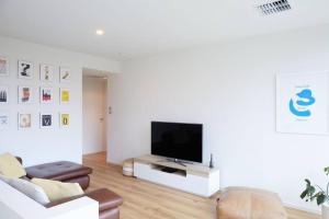 a living room with a flat screen tv on a white wall at Ripple at Port Willunga in Port Willunga