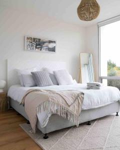 a white bedroom with a large bed with white sheets at Ripple at Port Willunga in Port Willunga