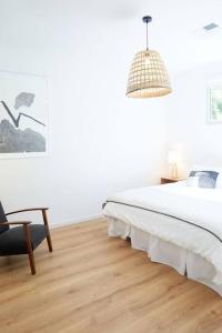 a white bedroom with a bed and a chair at Ripple at Port Willunga in Port Willunga