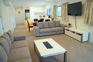 Una sala de estar con un sofá y un televisor. en Large Group Greymouth accommodation 2 houses with 7 bedrooms 6 queens 6 single beds 5 bathrooms 5 toilets, en Greymouth