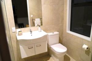 Un baño con inodoro, lavabo y espejo. en Large Group Greymouth accommodation 2 houses with 7 bedrooms 6 queens 6 single beds 5 bathrooms 5 toilets, en Greymouth 20 fotos más