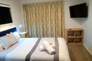 Un dormitorio con una cama con dos toallas encima. en Large Group Greymouth accommodation 2 houses with 7 bedrooms 6 queens 6 single beds 5 bathrooms 5 toilets, en Greymouth