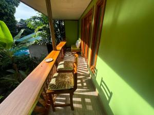 a balcony with benches and a green wall at Chilamate Room 2 in Tortuguero
