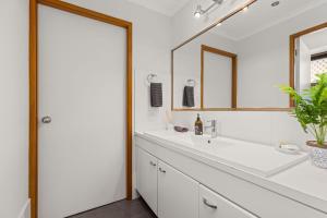 a white bathroom with a sink and a mirror at Colloden Beach House by Experience Jervis Bay in Vincentia +14 photos