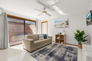 a living room with a couch and a window at Colloden Beach House by Experience Jervis Bay in Vincentia