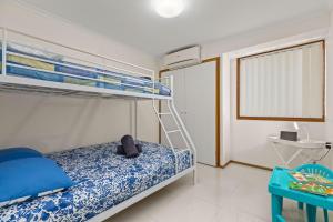 a bedroom with a bunk bed and a blue table at Colloden Beach House by Experience Jervis Bay in Vincentia