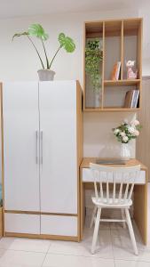 une armoire blanche à côté d'une table et d'une chaise dans l'établissement AnChi Home - Garden view- Căn hộ 2 giường đẹp - Ocean Park Gia Lâm, à Hanoï