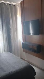 a bedroom with a bed and a tv on the wall at Apartamento Villamares Ataláia in Luis Correia
