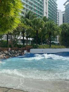 a river with waves and palm trees and buildings at The Bahamas & Maldives Suites at Azure Residences near Manila Airport in Manila