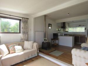 a living room with a couch and a kitchen at Rustic Charmer in Cable Bay in Cable Bay