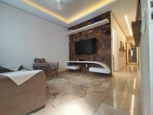 a living room with a stone wall with a tv at Casa para descanso e tranquilidade in Uberaba