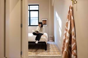 a woman sitting on a bed reading a book at Little Drifter Melbourne in Melbourne +45 photos