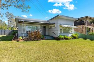 una casa blanca con césped delante en Huskisson Delight! by Experience Jervis Bay, en Huskisson