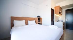 a bedroom with a large white bed and a kitchen at Simple and Comfortable Studio Apartment at Suncity Residence By Travelio in Sidoarjo +11 photos