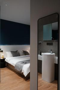 ein Schlafzimmer mit einem Bett, einem Waschbecken und einem Spiegel in der Unterkunft 画舍 Colorstory Hotel in Hangzhou + 45 Fotos