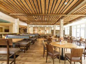 restauracja z drewnianymi sufitami, stołami i krzesłami w obiekcie Hotel Sportwelt w mieście Zauchensee